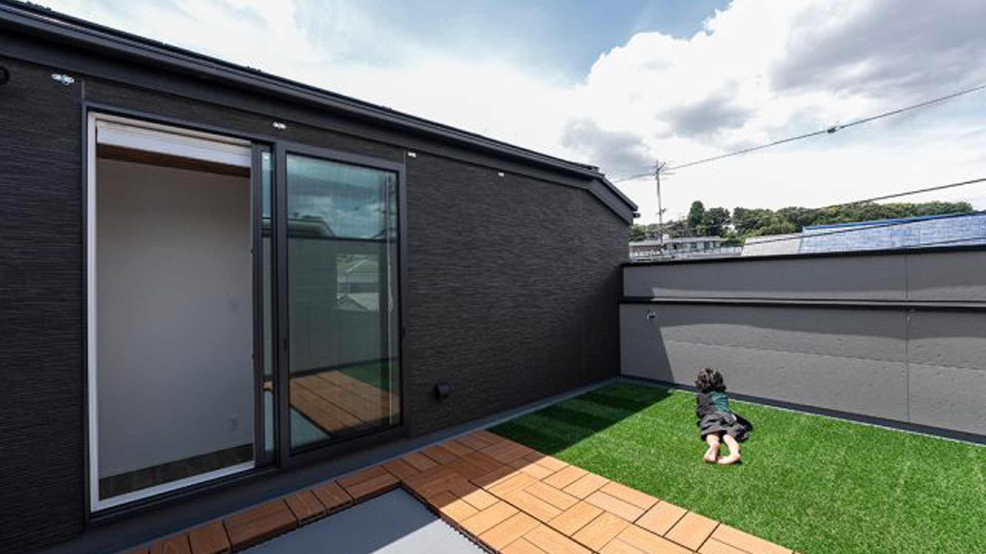 モダンな屋上庭園。人工芝と木製デッキの組み合わせが美しく、プライベート感のある屋外スペース