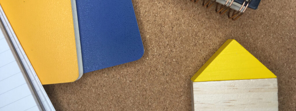 コルクボードの上に置かれた黄色い屋根の模型