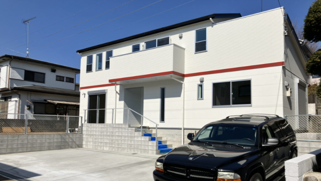 赤ラインが特徴的な白い外観の新築住宅