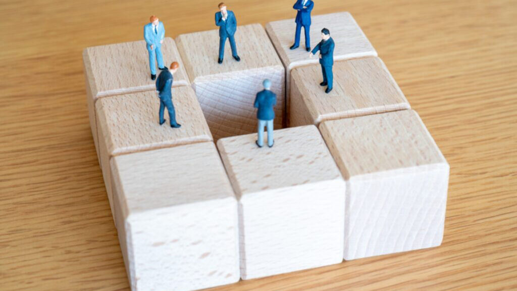 木製ブロックの上に立つビジネスマンの人形モデル