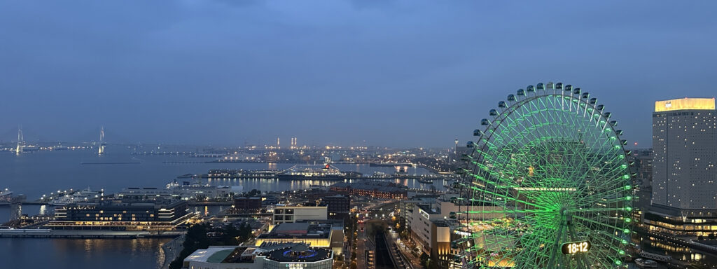 夜景で光る緑色の観覧車と都市風景