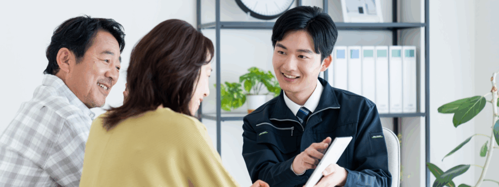 タブレットを使い夫婦に説明する作業着の男性