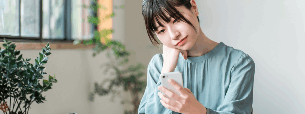 スマートフォンを見ながら物思いにふける若い女性