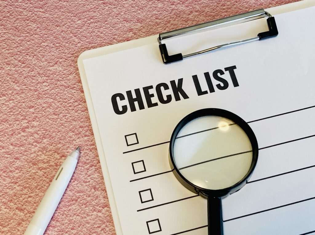 チェックリストと虫眼鏡、ペン│最終確認のためのチェックリストのイメージ